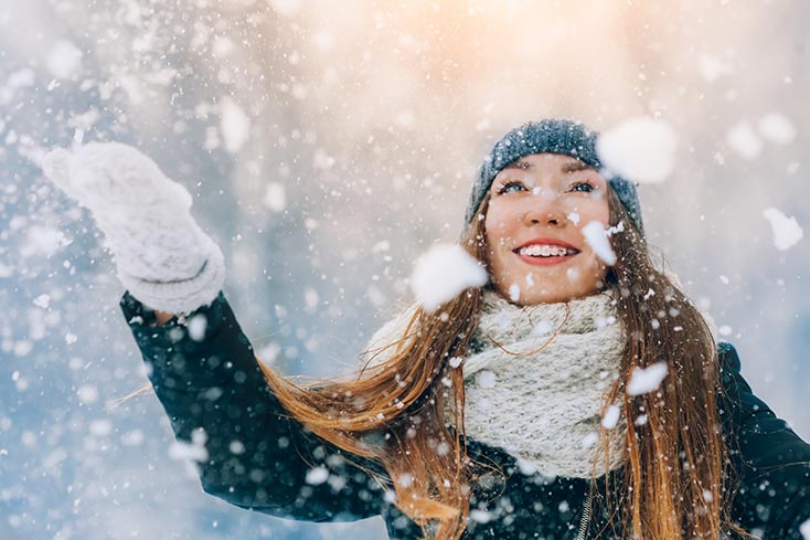 A woman is having fun with snowflakes. Happy and healthy.